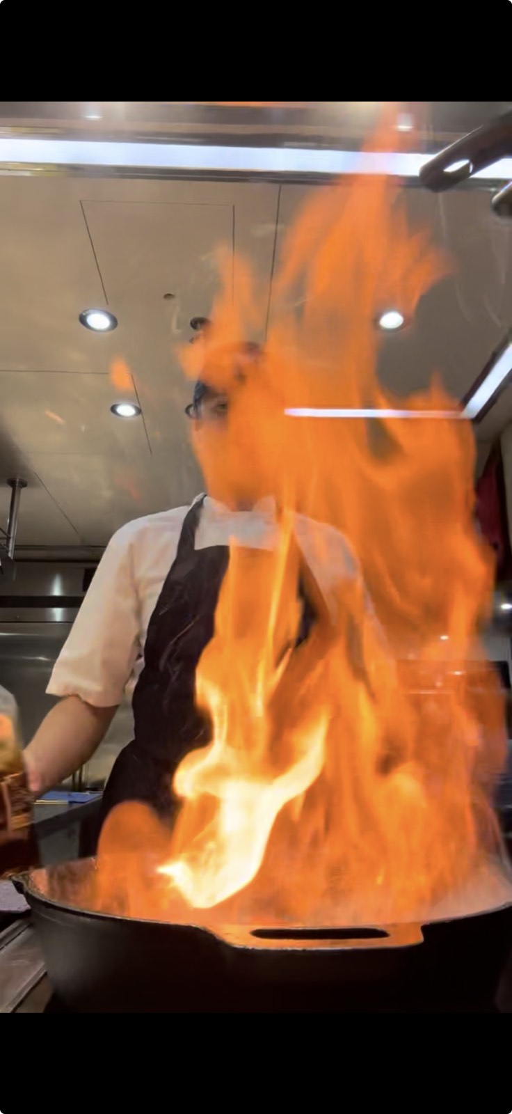 Hands working over open flame in a professional kitchen