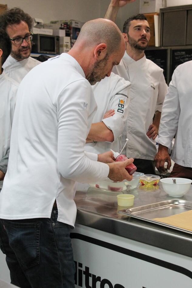 Martin Lippo piping a preparation while chefs watch from across the bench