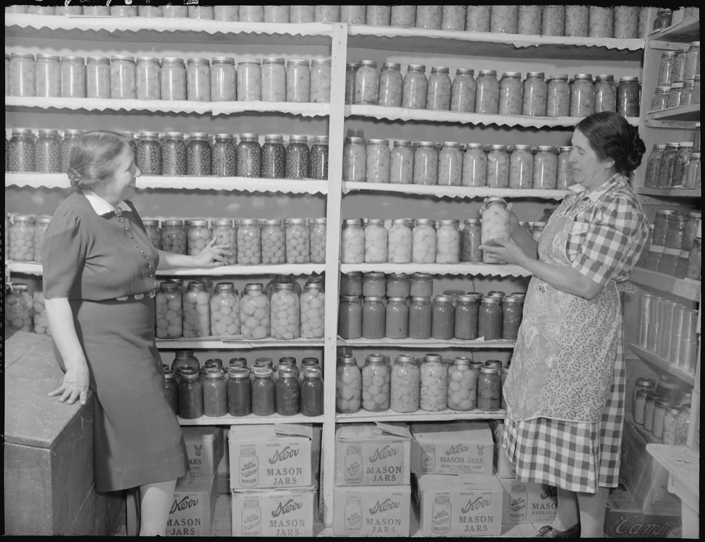 Two women in a 1946 New Mexico pantry stocked with home-canned fruit and vegetables